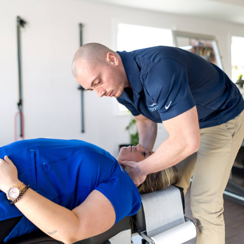 Chiropractor Dr. Tim Lyons providing treatment to a female patient at a clinic.