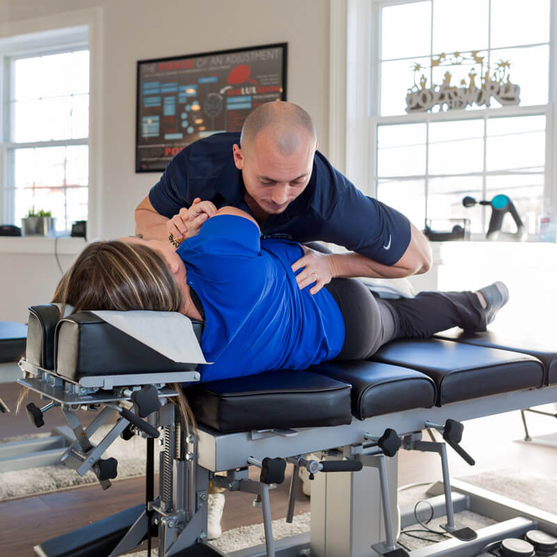 Dr. Tim Lyons, chiropractor, performing an adjustment on a patient at 'The Chiropractic Source' clinic.