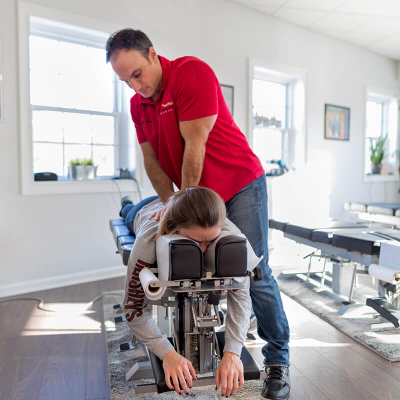 Dr. Marco Ferrucci, chiropractor, treating a female patient on an adjustment table.